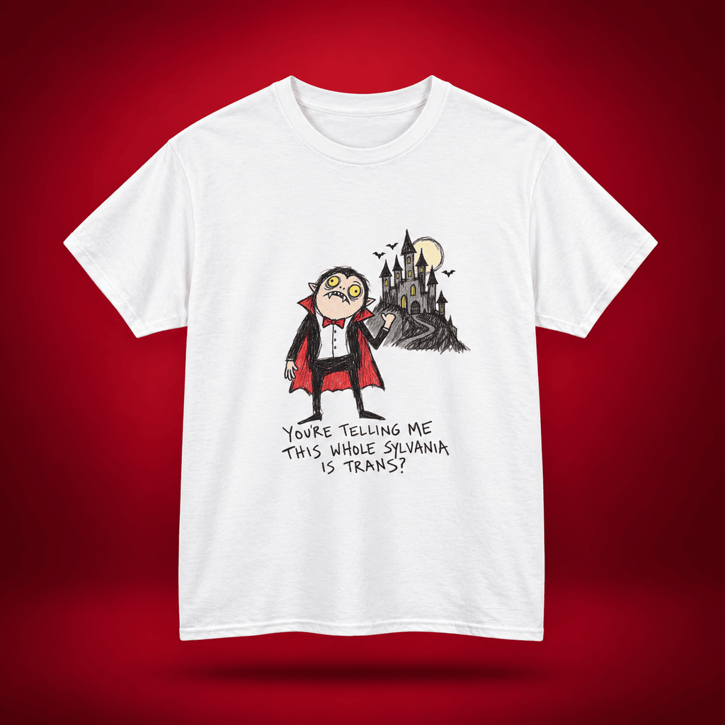 A white short-sleeve crewneck t-shirt featuring a cartoon graphic of a vampire looking surprised next to a haunted castle, with the text 'YOU'RE TELLING ME THIS WHOLE SILVANIA IS TRANS?' printed below. The t-shirt is displayed against a dark red gradient background.