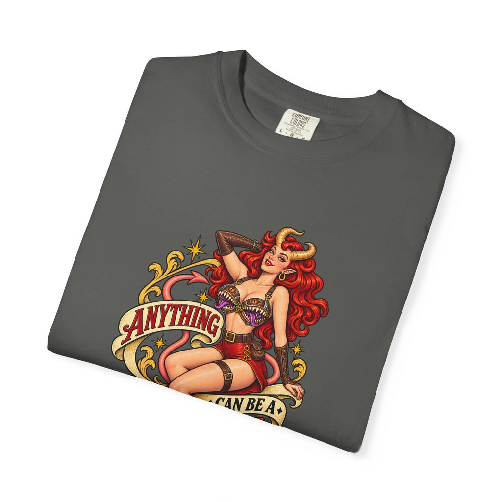 A dark gray folded t-shirt featuring a colorful retro pin-up style graphic of a horned woman with red hair and the text 'ANYTHING I CAN BE A MIMIC'.