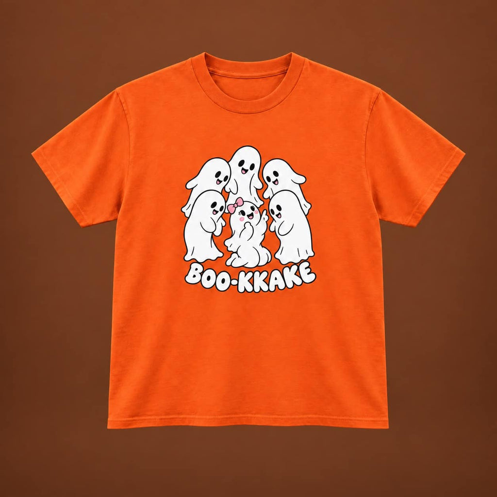 An orange short-sleeve t-shirt with a cartoon graphic of five white ghosts and the text 'BOO-KKAKE' printed on the front, displayed against a solid brown background.