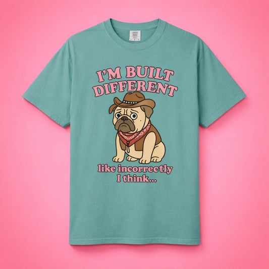 Flat lay of the teal Built Incorrectly Pug Shirt against a pink studio background.