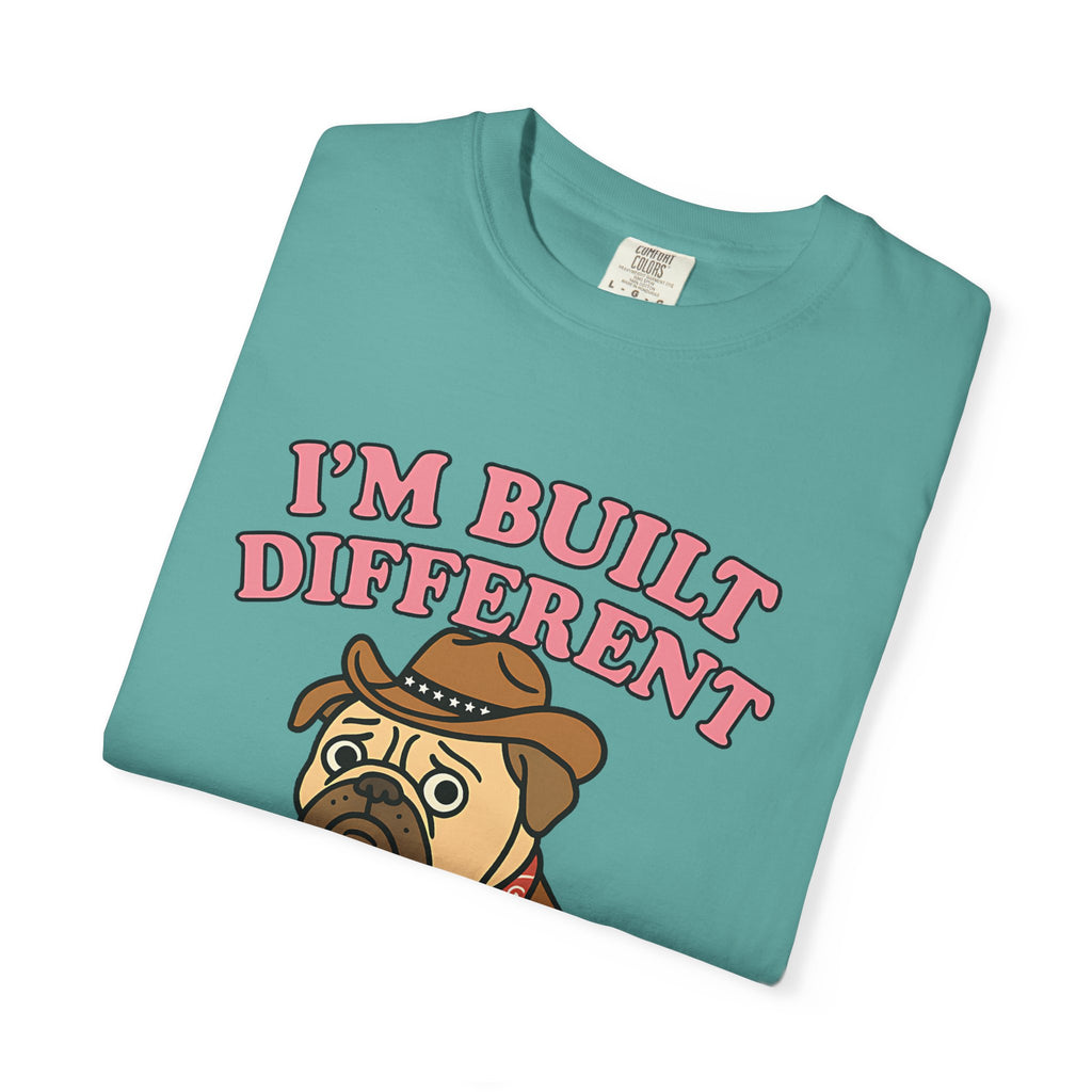 Folded teal t-shirt showing close-up of the sad pug face and pink bubble text.