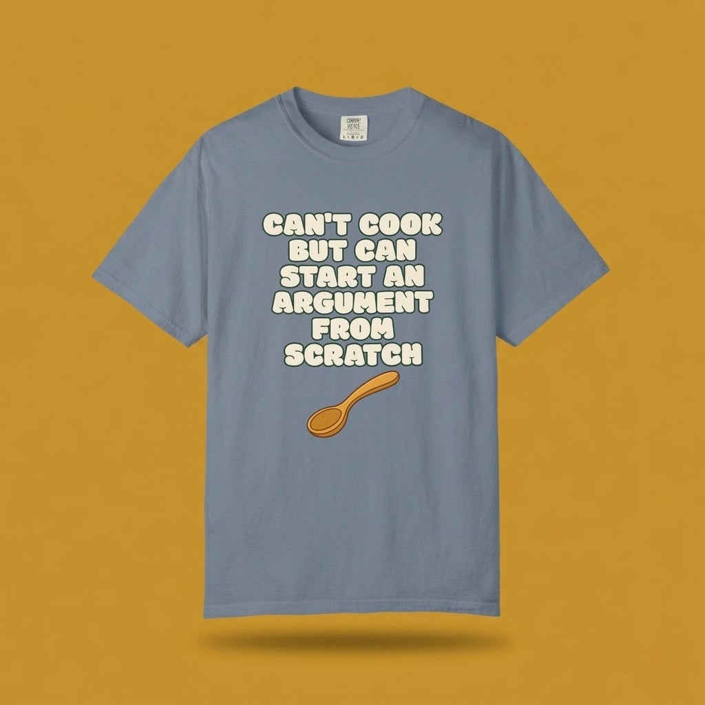 Blue graphic t-shirt flat lay on yellow background featuring Can’t Cook slogan.
