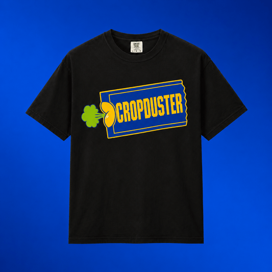 Flat lay mockup of the black Cropduster pop culture joke shirt centered on a vibrant royal blue gradient background.
