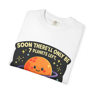 Neatly folded white t-shirt showing a cute orange planet graphic and a dirty astronomy joke.