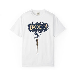 Flat lay of a white t-shirt featuring a magic wand and swirling Engorgio spell text.