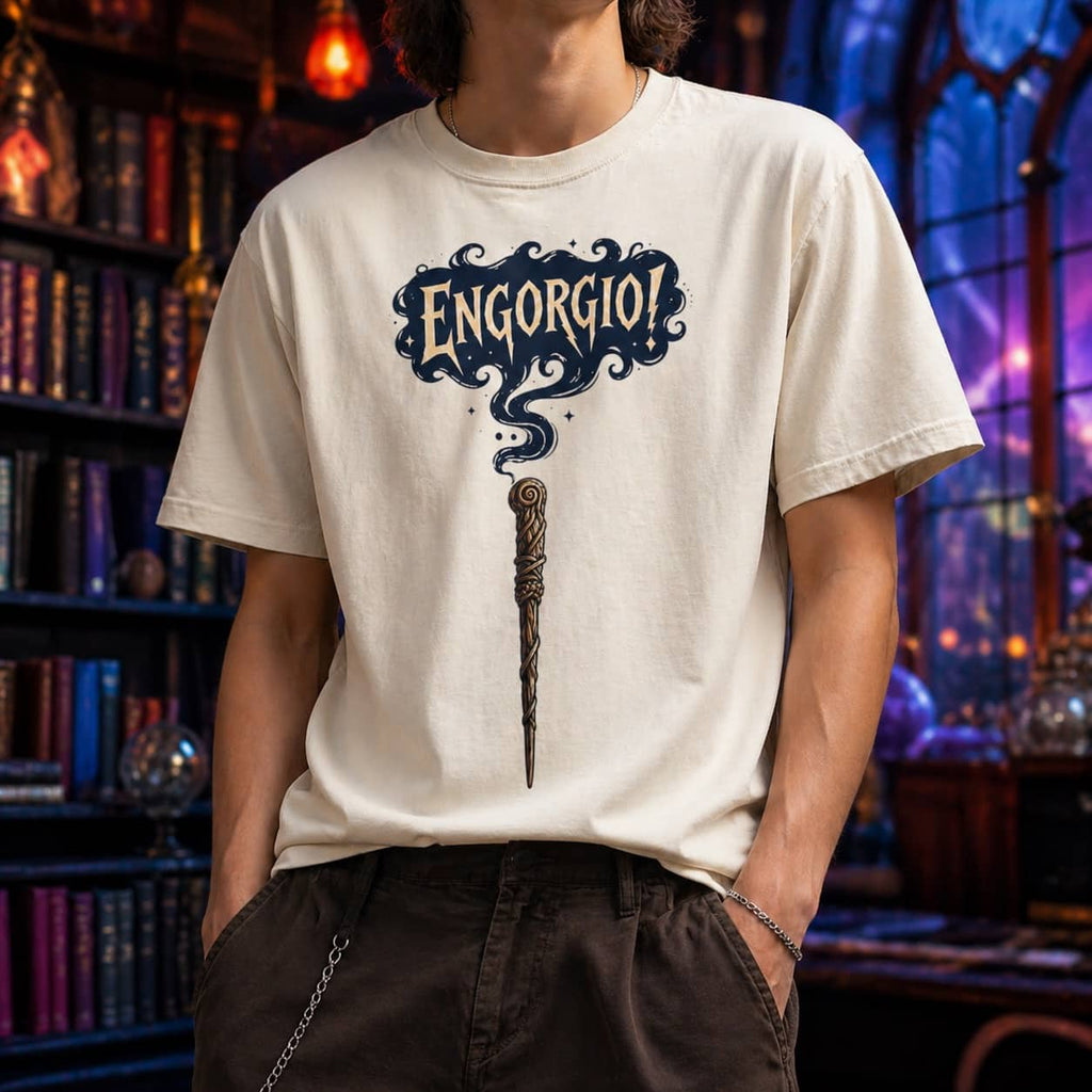 Model wearing the cream-colored Engorgio magic wand graphic t-shirt in a magical, dimly lit library setting.