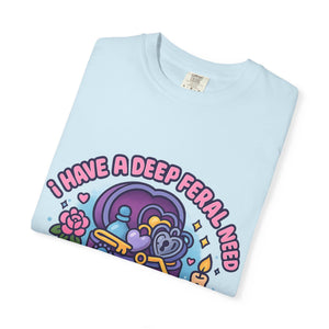 Folded light blue cotton tee with 'I Have A Deep Feral Need For Antique Trinkets' graphic