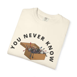 Folded ivory graphic t-shirt featuring box of random cables. 