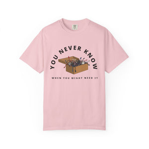 Flat lay of pink graphic t-shirt on white background featuring box of random cables.