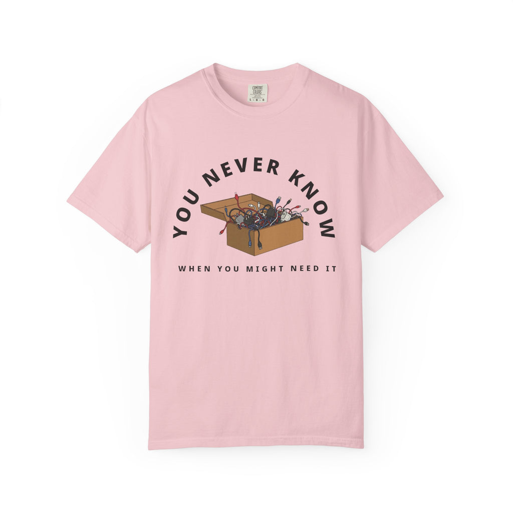 Flat lay of pink graphic t-shirt on white background featuring box of random cables.