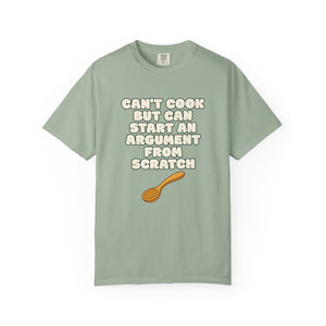 Flat lay of green graphic t-shirt on white background featuring Can’t Cook slogan.