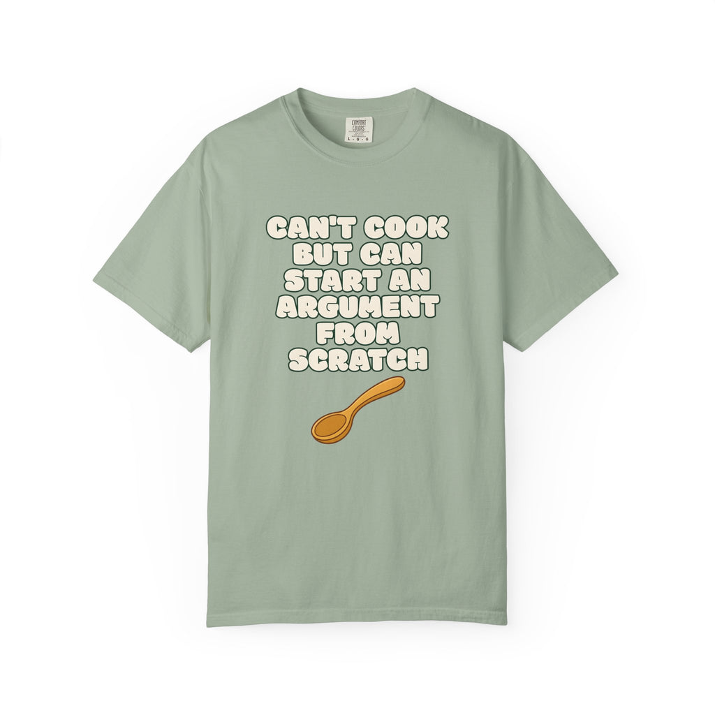 Flat lay of green graphic t-shirt on white background featuring Can’t Cook slogan.