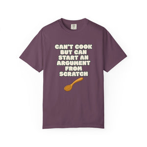 Flat lay of purple graphic t-shirt on white background featuring Can’t Cook slogan.