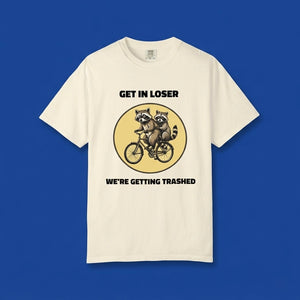 Ivory graphic t-shirt flat lay on blue background featuring Get In Loser We’re Getting Trashed meme design.
