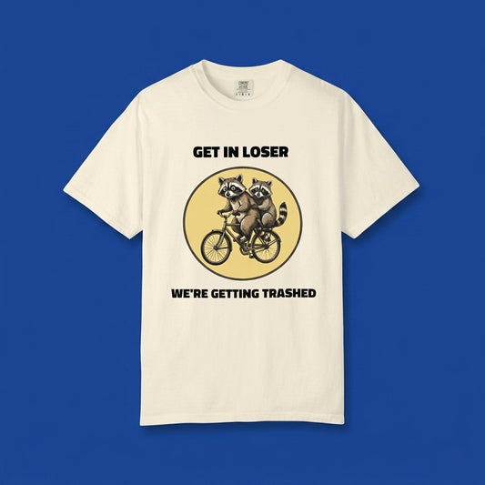 Ivory graphic t-shirt flat lay on blue background featuring Get In Loser We’re Getting Trashed meme design.