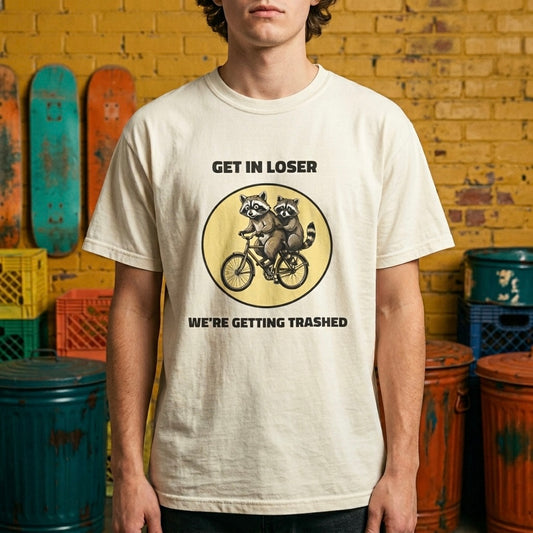Ivory graphic t-shirt flat lay on blue background featuring Get In Loser We’re Getting Trashed meme design.