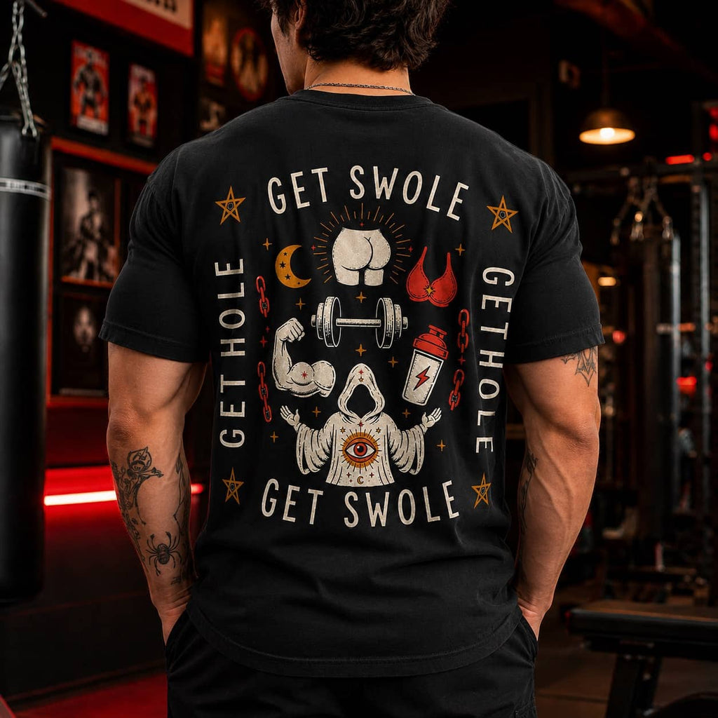 Muscular male model standing in a dark, neon-lit gym wearing the Get Swole Get Hole occult meme t-shirt, showing the back graphic.
