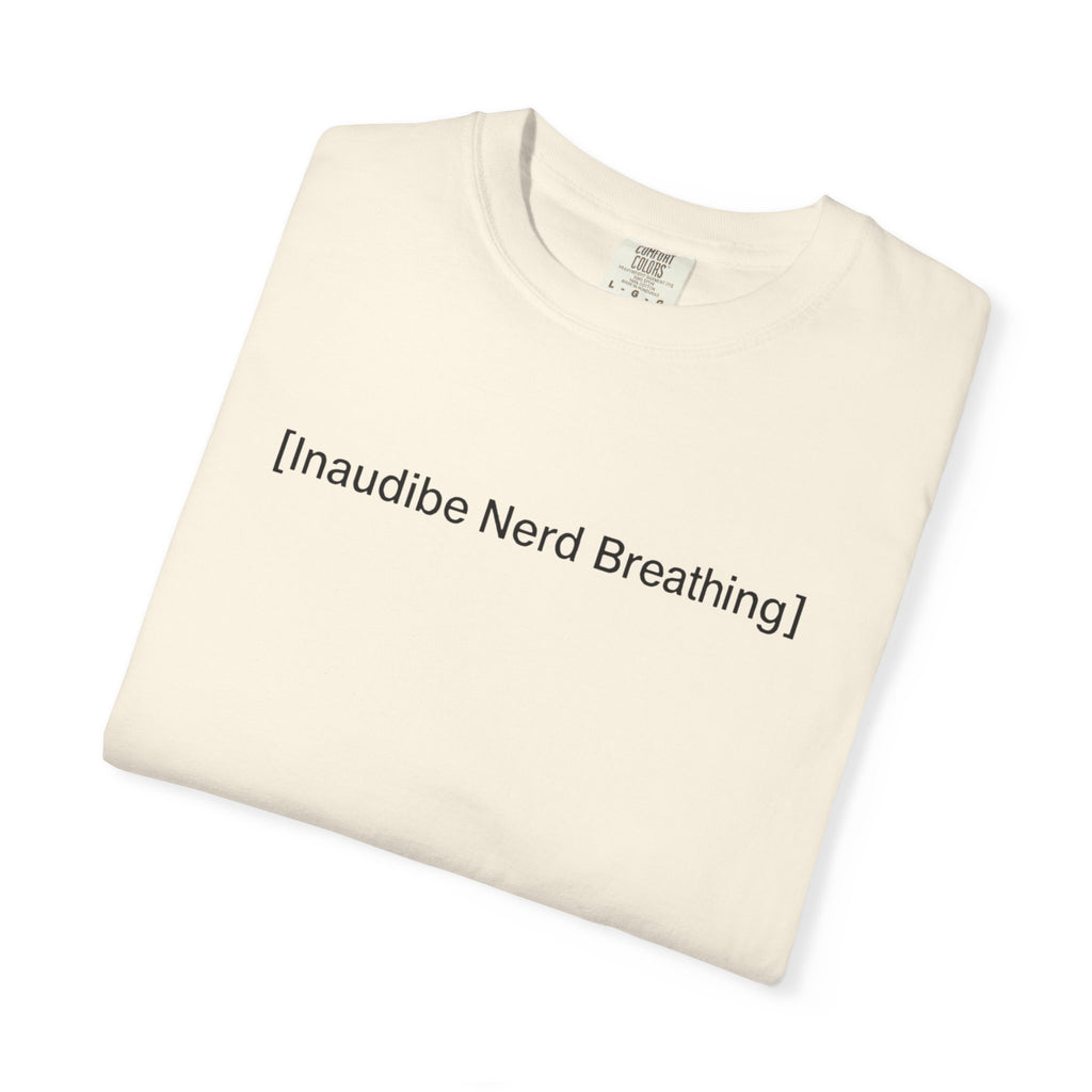 Folded cream-colored T-shirt with the text [Inaudible Nerd Breathing] printed in the center
