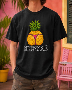 Male model standing outdoors wearing a black Fineapple t-shirt featuring a cheeky pineapple graphic in a pink thong.