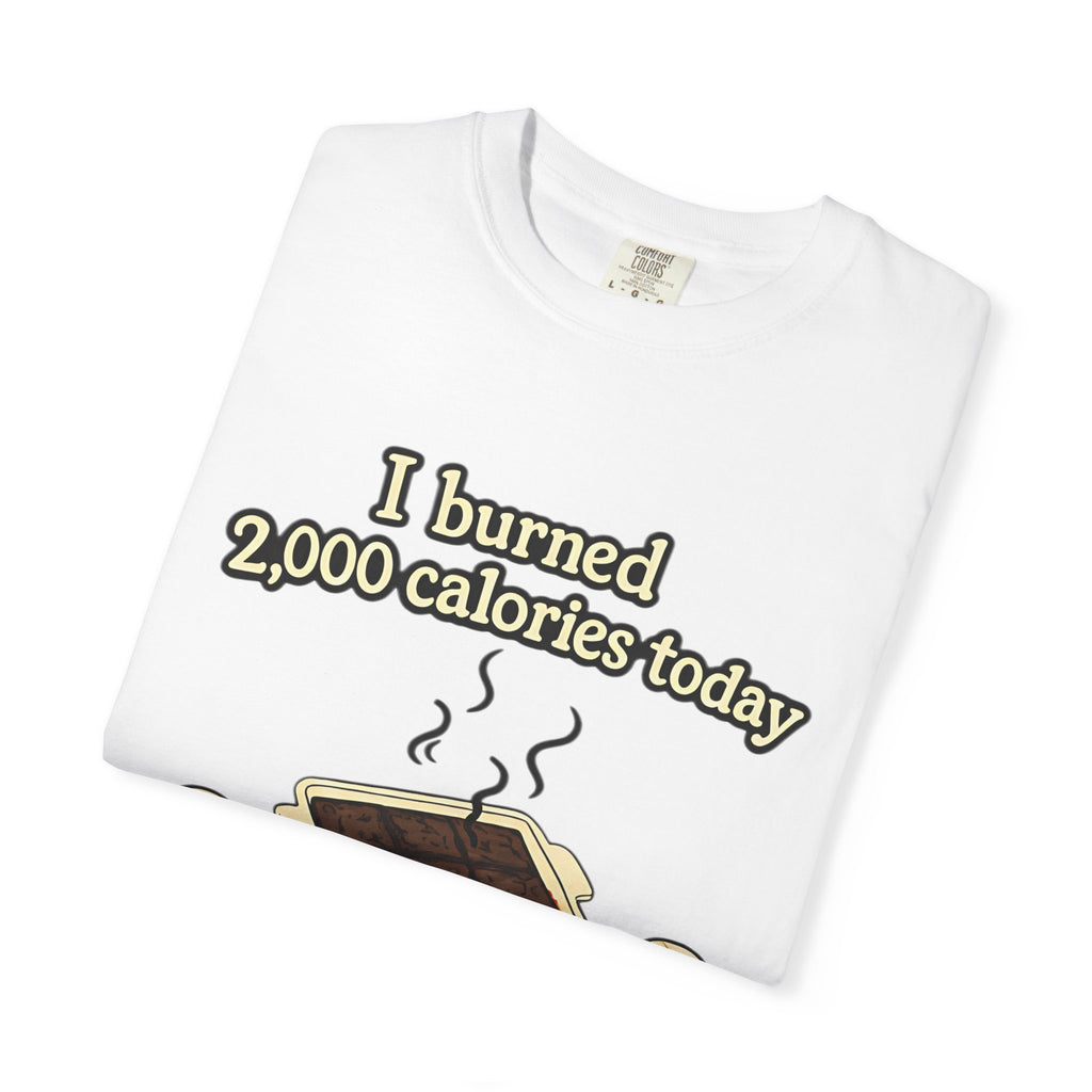 A folded white Comfort Colors t-shirt with a high-quality print of a tray of burnt brownies and a funny calorie-burning joke.