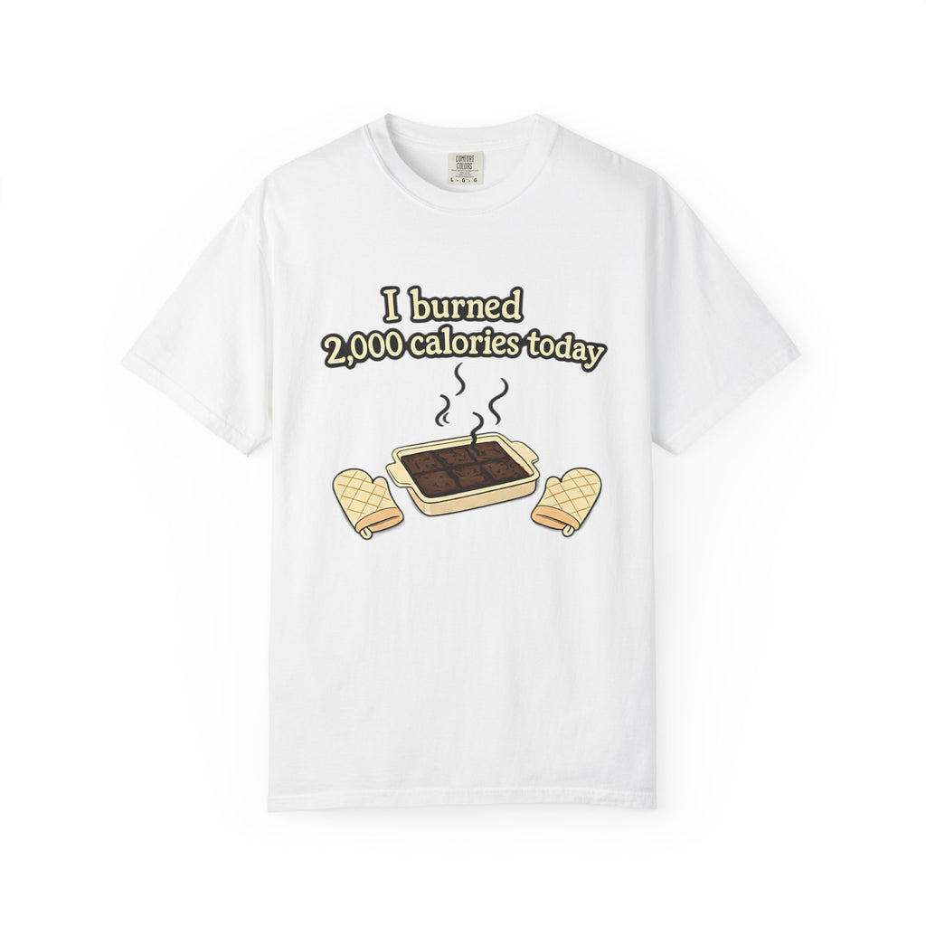 A clean white t-shirt displayed flat, printed with a humorous baking illustration of a pan of burnt brownies and oven mitts.