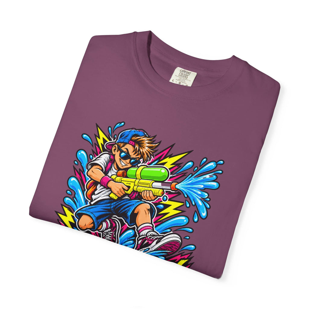 A folded maroon crewneck t-shirt featuring a colorful cartoon graphic of a boy playing with a water gun, shown on a plain white background.