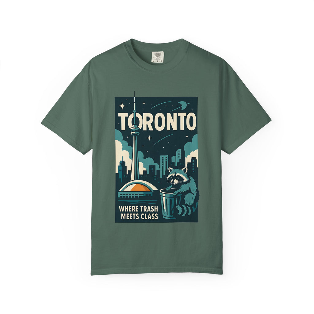 Flat lay of a sage green Comfort Colors t-shirt featuring a retro Toronto skyline and a raccoon in a trash can.