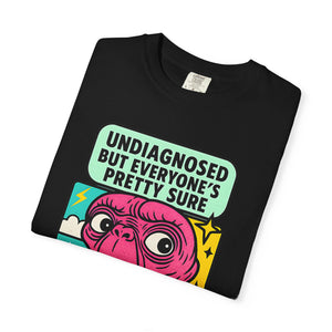 Flat lay of folded black Comfort Colors t-shirt featuring pink alien and "Undiagnosed" text.