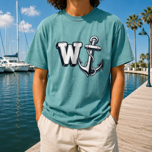 Model wearing a seafoam green Comfort Colors 1717 t-shirt with the W Anchor meme design, standing on a wooden boardwalk near boats and a marina.